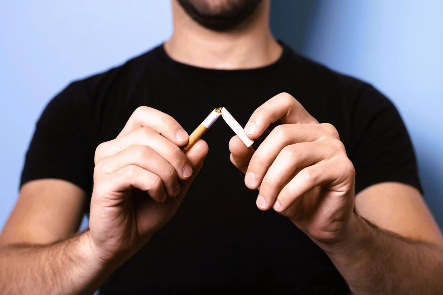Man breaks cigarette to signify quitting smoking with help from infrared sauna sessions